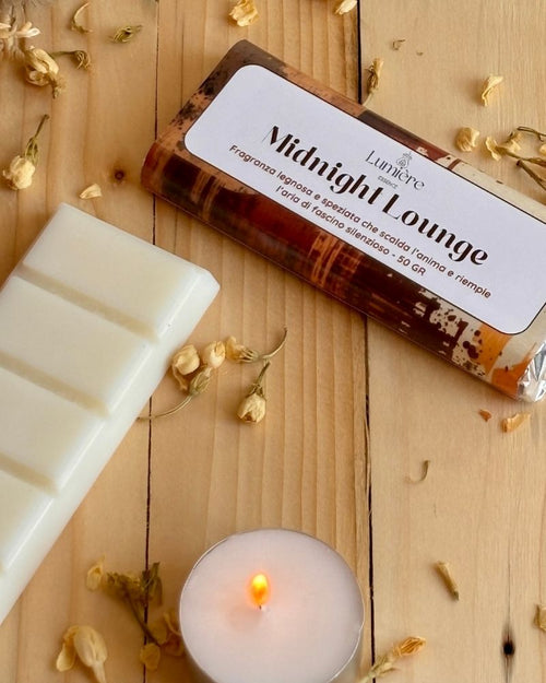 Barretta Midnight Lounge vista da vivino con fiori decorativi e candelina accesa, la barretta ha una profumazione seducente che trasmette lusso ed eleganza