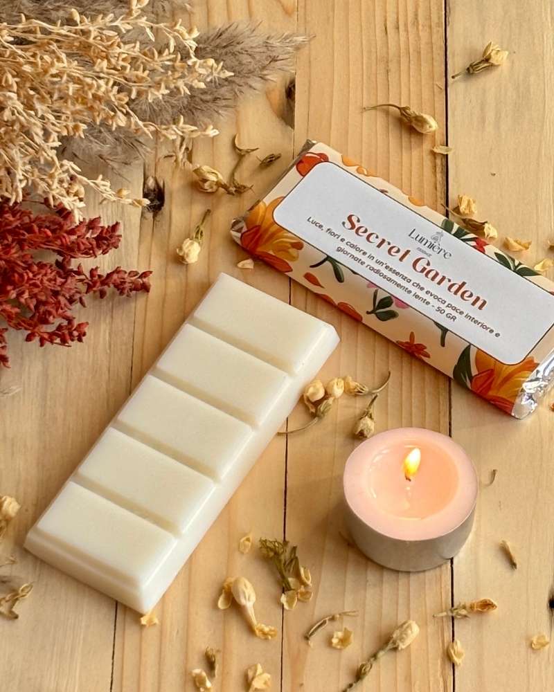 Barretta Secret Garden Lumiere Essence con etichetta frontale una piccola candela e fiori decorativi