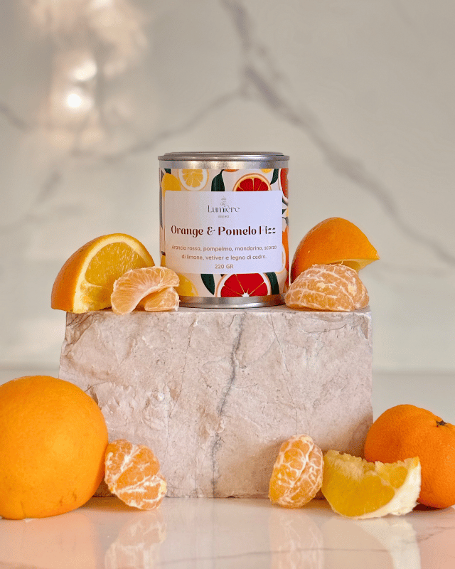 Candela realizzata in cera di cocco naturale cera di cocco, un barattolo di latta  su pietra di marmo sullo sfondo arance pompelmi mandarino 