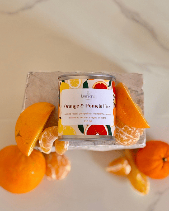 Candela realizzata in cera di cocco naturale cera di cocco, un barattolo di latta  su pietra di marmo sullo sfondo arance pompelmi mandarino vista dall'alto