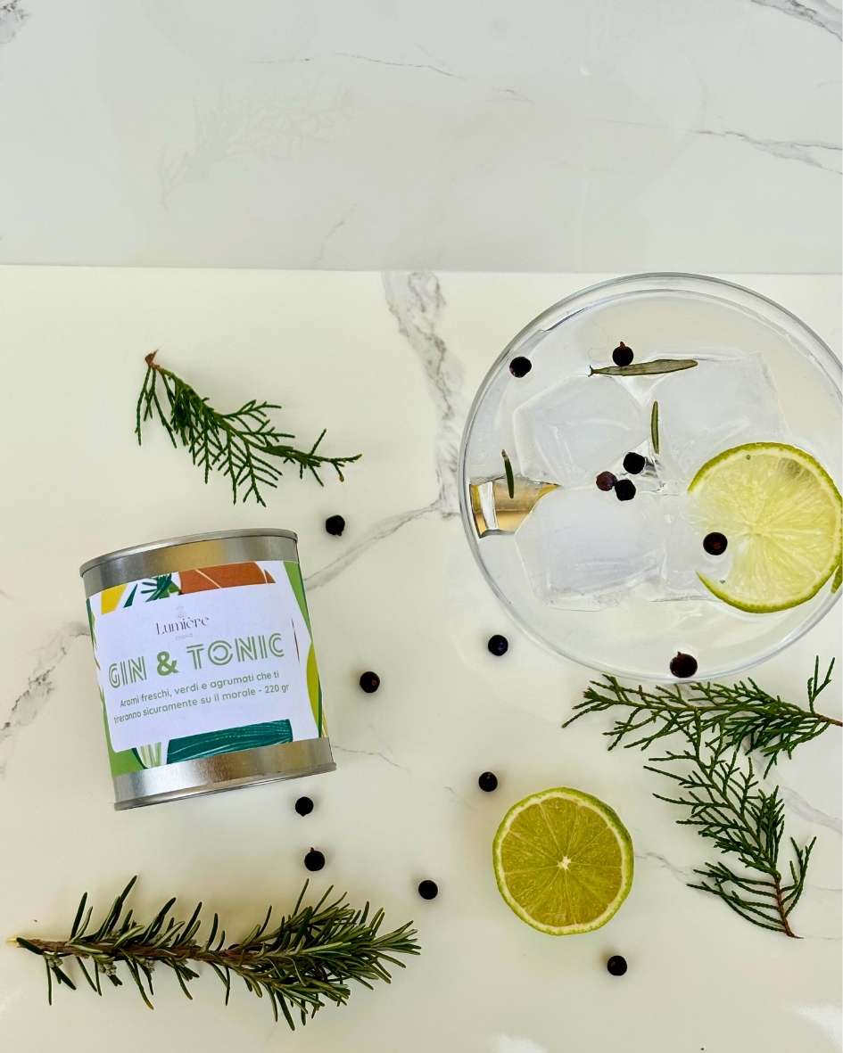 Candela Gin&Tonic Lumière Essence -  barattolo con attorno rosmarino ginepro e lime su un piano di marmo
