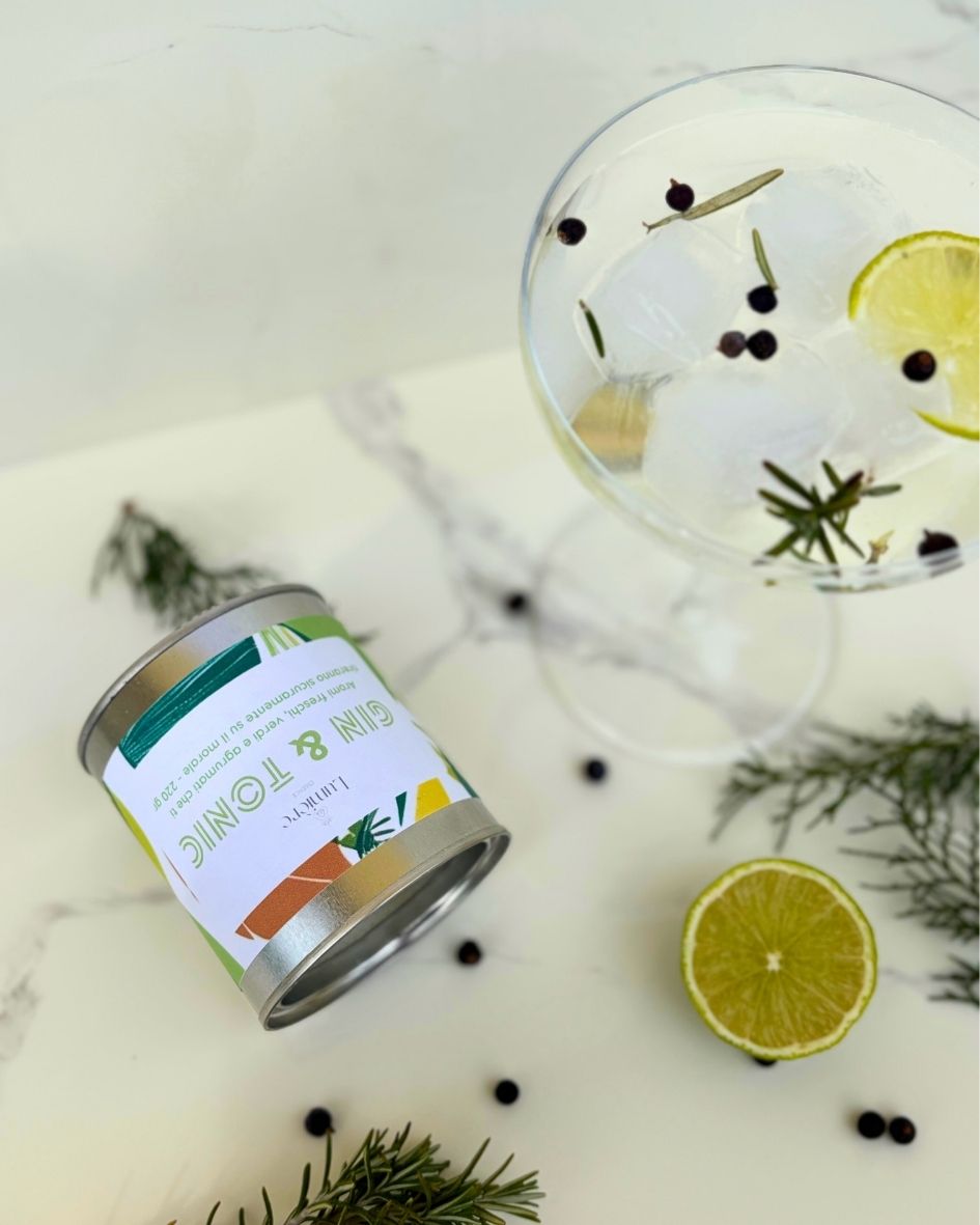 Candela Gin&Tonic Lumière Essence -  barattolo con attorno rosmarino ginepro e lime su un piano di marmo