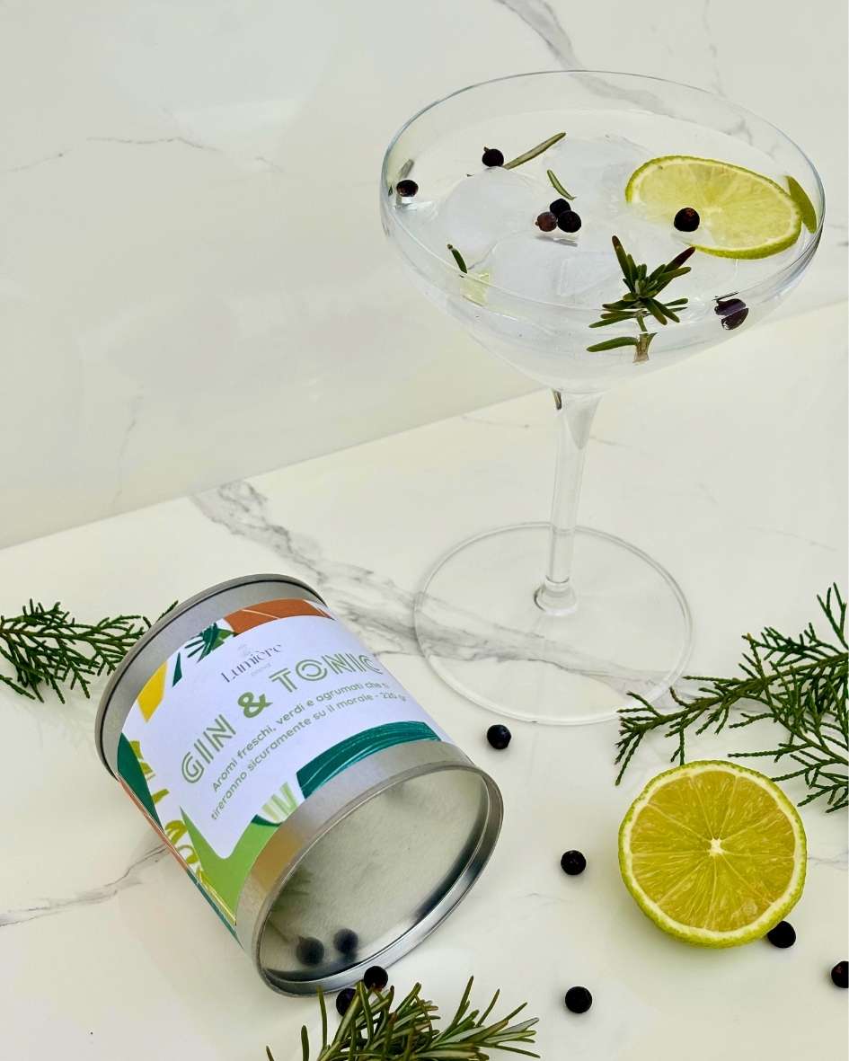 Candela Gin&Tonic Lumière Essence -  barattolo con attorno rosmarino ginepro e lime su un piano di marmo