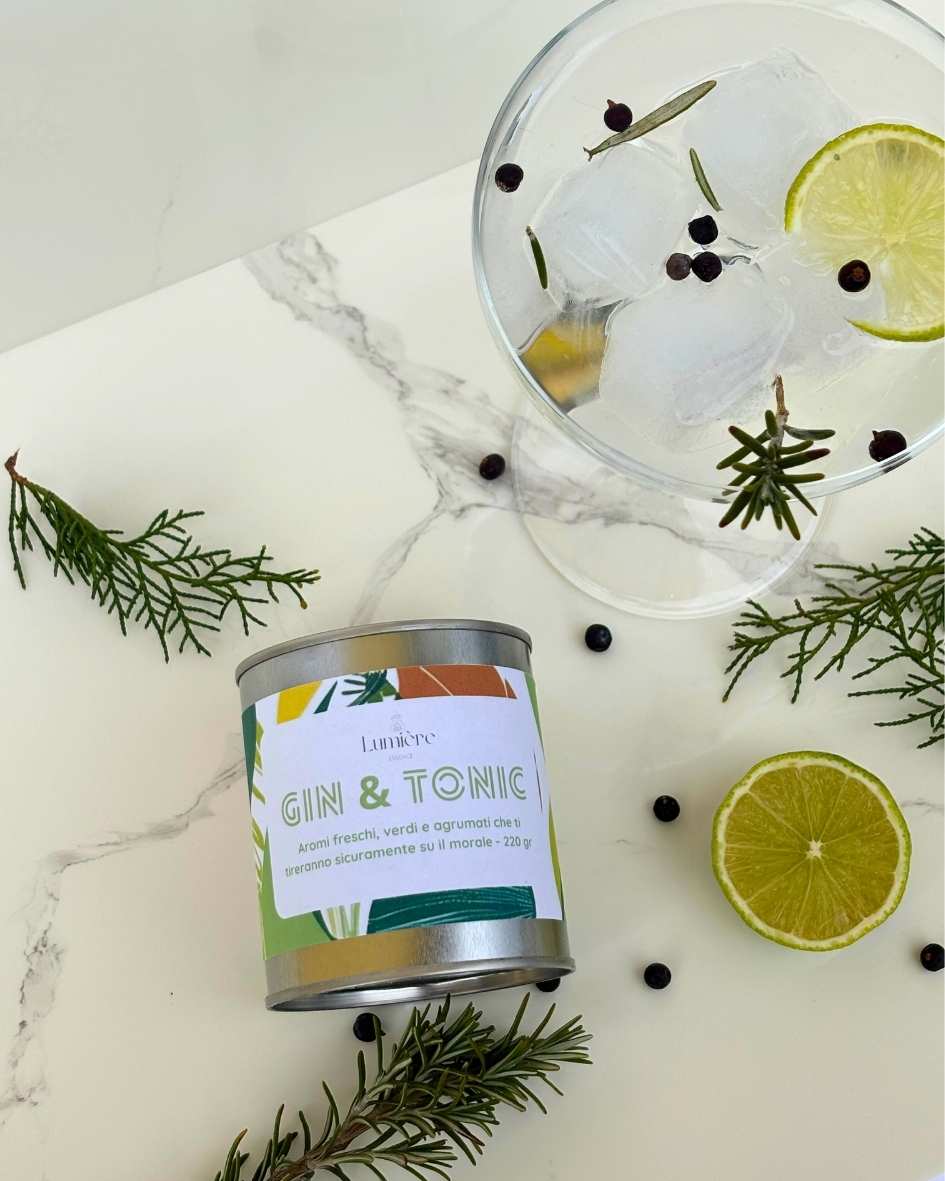 Candela Gin&Tonic Lumière Essence -  barattolo con attorno rosmarino ginepro e lime su un piano di marmo