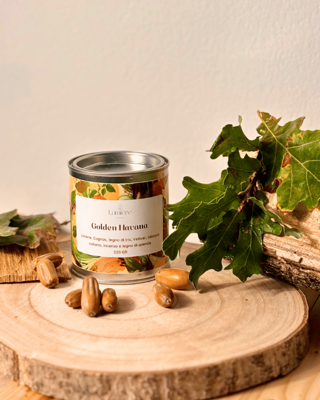 Candela in atmosfera autunnale, con foglie, semi e legno di quercia, che riflettono la fragranza.