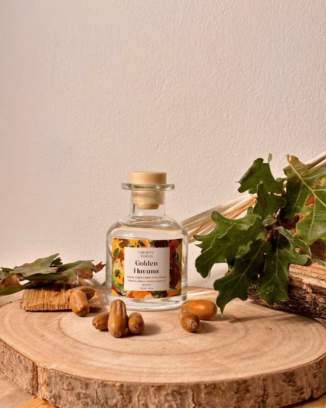 Diffusore a bastoncino in bottiglietta di vetro in sfondo autunnale e foglie, semi e legno di quercia