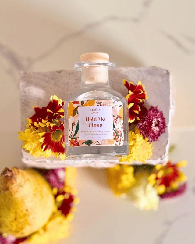 Diffusore a bastoncino in bottiglietta di vetro sullo sfondo pere, fiori e una pietra in marmo e inquadratura dall'alto