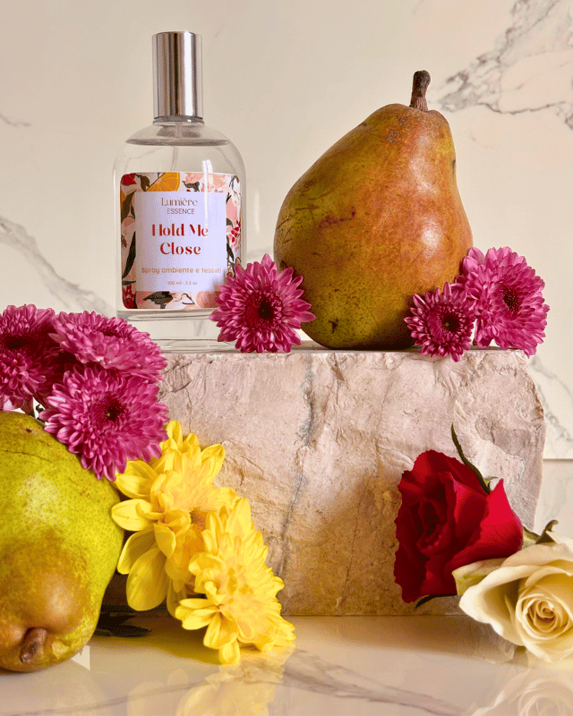 Spray per tessuti e ambiente n bottiglietta di vetro con pere e fiori su pietra di marmo