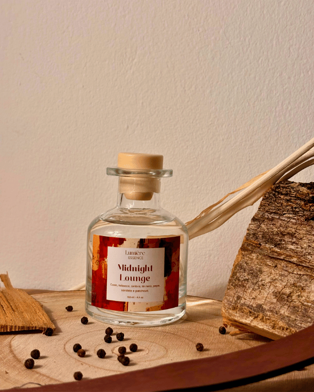 Diffusore a bastoncini in bottiglietta di vetro con ambientazione invernale con legno di sandalo e chicchi di pepe