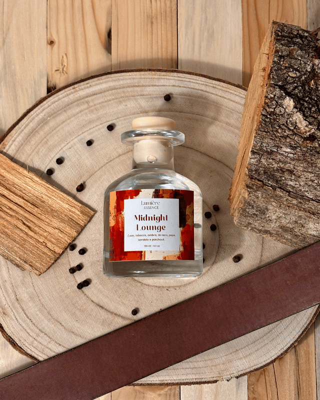 Diffusore a bastoncini in bottiglietta di vetro con ambientazione invernale con legno di sandalo e chicchi di pepe con foto dall'alto