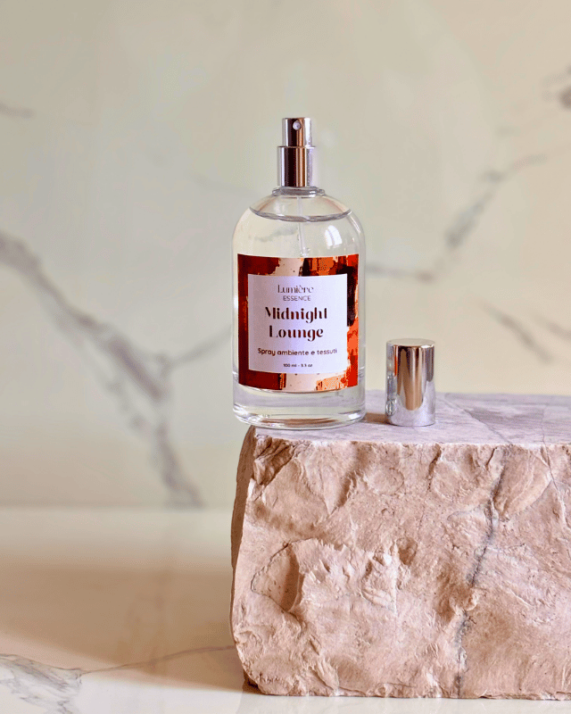 Spray per ambiente in bottiglietta di vetro con spruzzatore visibile su pietra di marmo