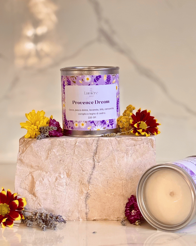 Candela in barattolo di latta realizzata in cera di cocco con fiori di lavanda e crisantemi su pietra di marmo e candela che mostra il suo interno