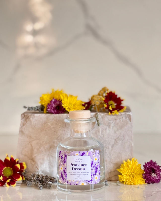 Diffusore per ambiente a bastoncino in bottiglietta di vetro sullo sfondo pietra di marmo fiori di lavanda fiori che rappresentano la fragranza