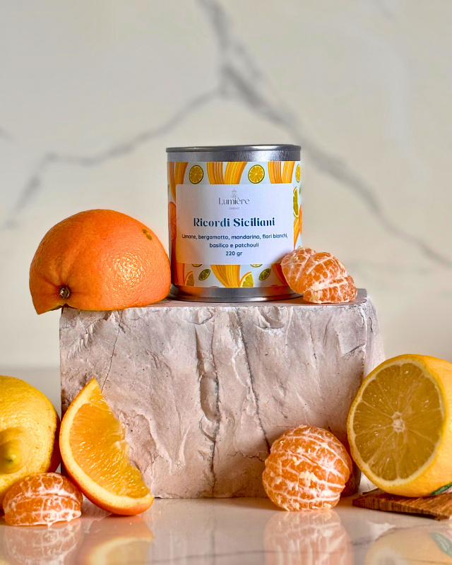 Candela in barattolo di latta realizzata in cera di cocco su pietra di marmo e agrumi che rappresentano la fragranza 