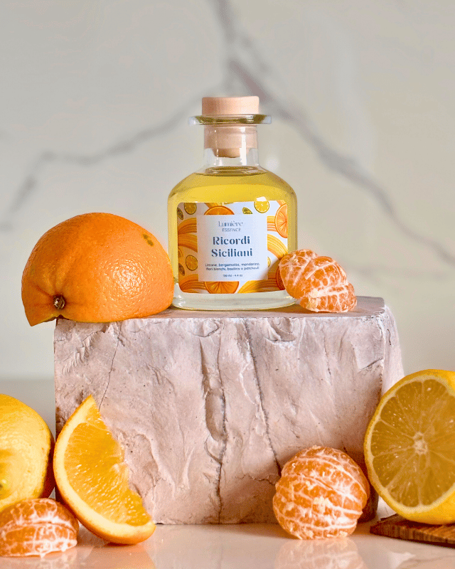 Diffusore per ambiente a bastoncino in bottiglietta di vetro sullo sfondo agrumi su pietra di marmo