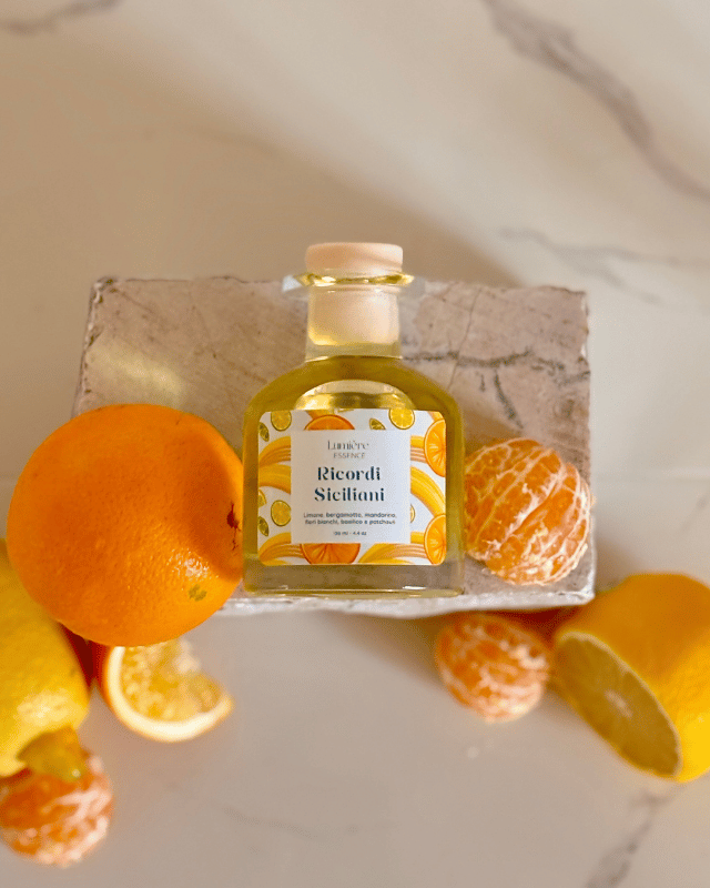 Diffusore per ambiente a bastoncino in bottiglietta di vetro sullo sfondo agrumi su pietra di marmo vista dall'alto