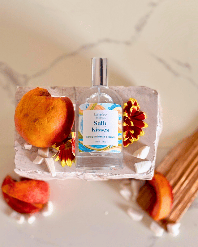 Spray per ambiente in bottiglietta di vetro su pietra di marmo con pesche e fiori