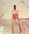 Flacone di spray profumo ambiente e tessuti Peachy Paradise, 100ml, sullo sfondo di tessuti colorati.